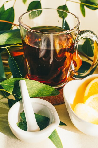 Tazza di tisana al limone e foglie di eucalipto in piccolo mortaio in ceramica bianca