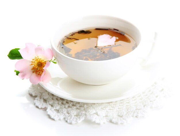 Cup of herbal tea with hip rose flowers isolated on white