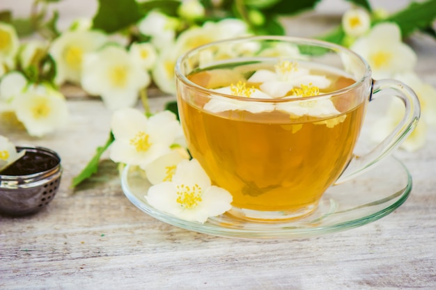 Tazza di tisana con fiori di gelsomino. messa a fuoco selettiva.