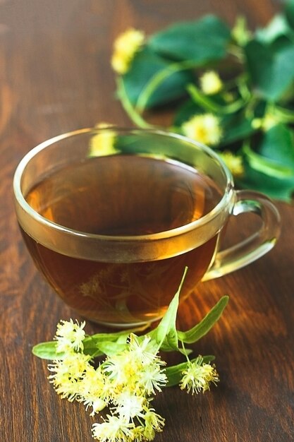 Cup of herbal tea with linden flowers on wooden table