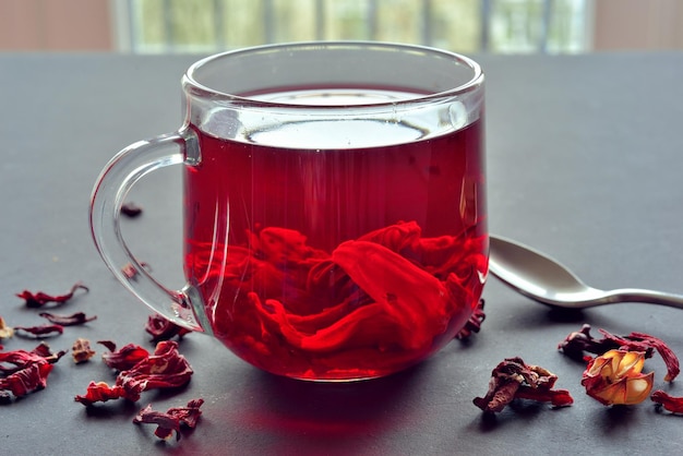 A cup of hibiscus tea with dry hibiscus tea around