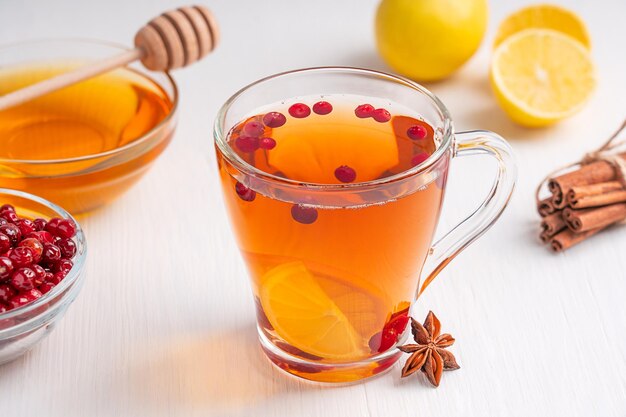 Cup of homemade healthy natural herbal tea made with cranberries, lemon slices, cinnamon and honey