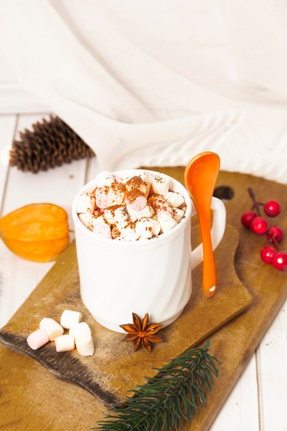 Photo cup of homemade hot chocolate on a wooden plate with color marshmallow