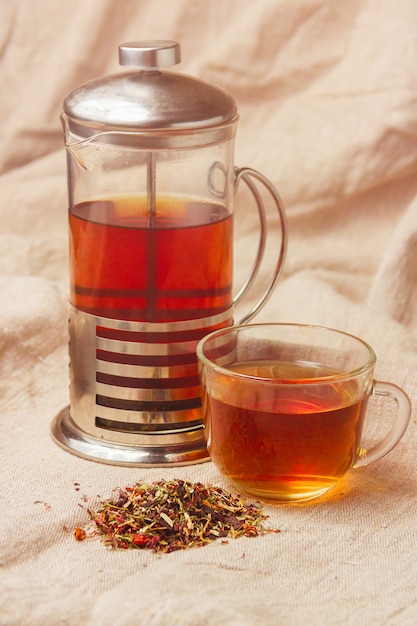 Cup of hot black tea, dried tea leaves on a light sackcloth 