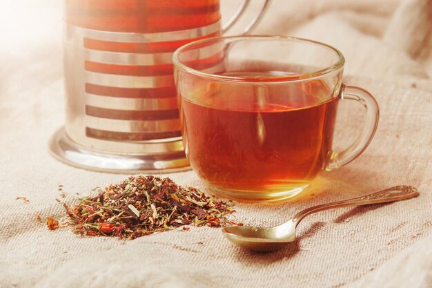 Cup of hot black tea, dried tea leaves on a light sackcloth 