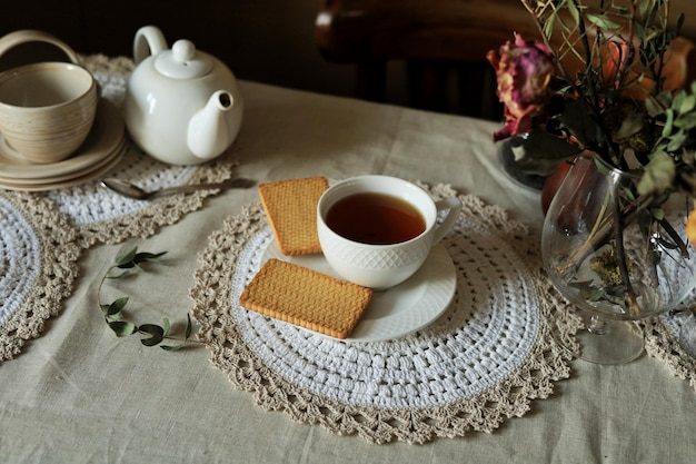 A cup of hot black tea on a saucer and cookies on the table Home still life