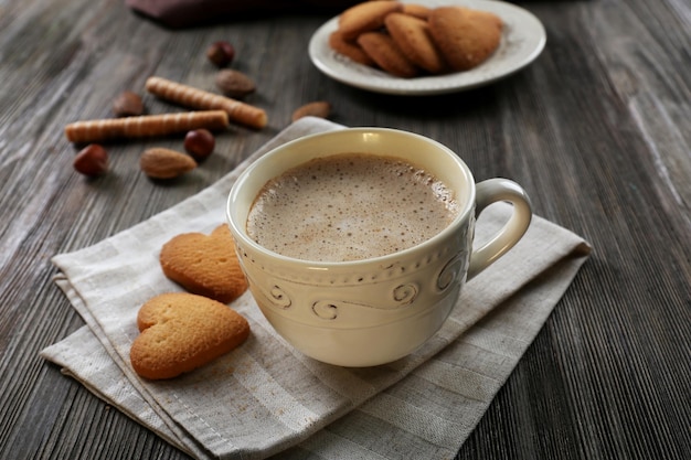 Cup of hot cacao on cotton serviette with cinnamon almonds and heart shaped cookies