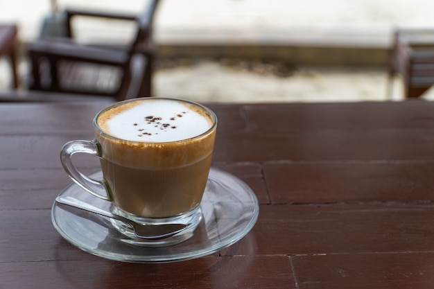 木製の机の上の熱いカプチーノコーヒーのカップ