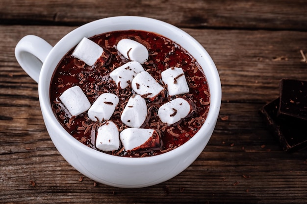 A cup of hot chocolate or cocoa with marshmallows on dark wooden background