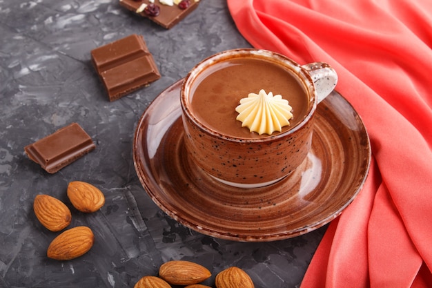 Cup of hot chocolate and pieces of milk chocolate with almonds