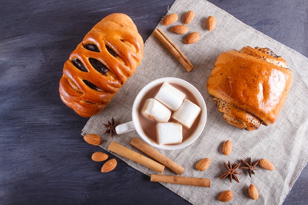 A cup of hot chocolate with marshmallow, buns, almonds and spices