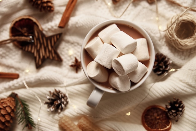 Cup of hot chocolate with a marshmallow and christmas decorations.