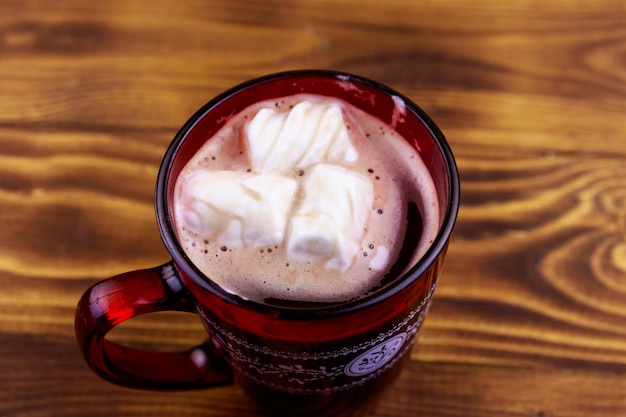 Cup of hot chocolate with melted marshmallow on wooden table