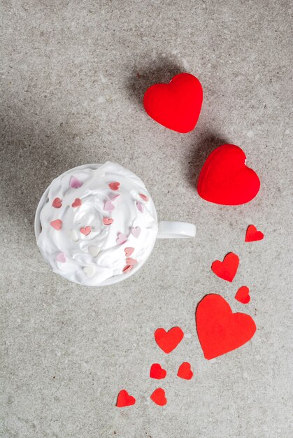 Cup for hot chocolate, with whipped cream and sweet hearts, with two plush red hearts