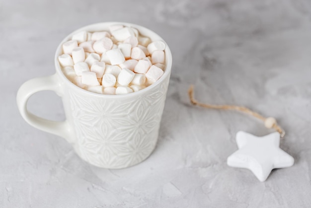 Cup of hot cocoa and marshmallows gray background