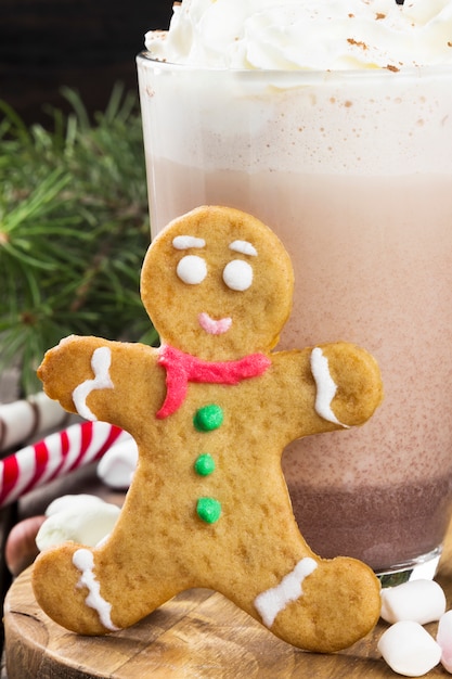 Cup of hot cocoa with cream and gingerbread on dark 