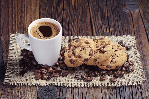 Cup of hot coffee and chocolate cookies on burlap