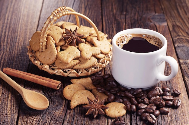 Cup of hot coffee and christmas cookies in wicker basket on old wooden table