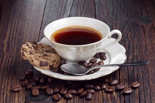 Cup of hot coffee and cookie with chocolate on dark wooden table