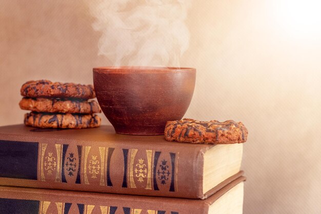 Cup of hot coffee and cookies on a stack of books breakfast in the library