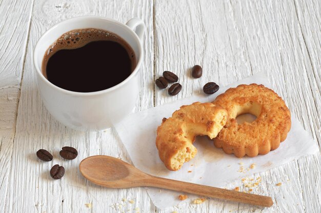흰색 나무 테이블에 아침 식사로 견과류와 함께 뜨거운 커피와 쿠키 한 잔
