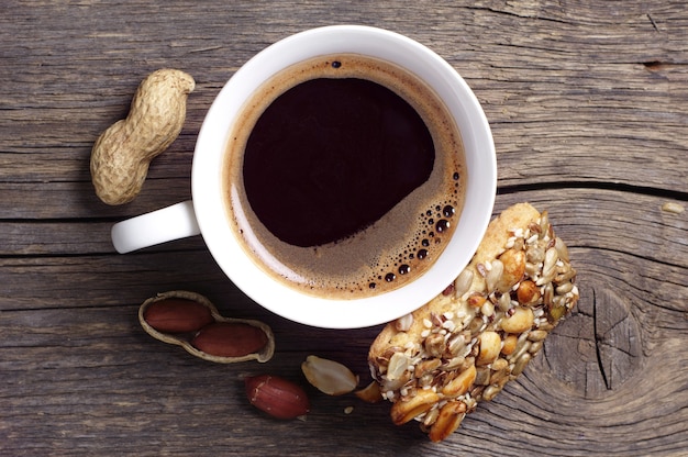 Cup of hot coffee and cookies with nuts on dark wooden table, top view
