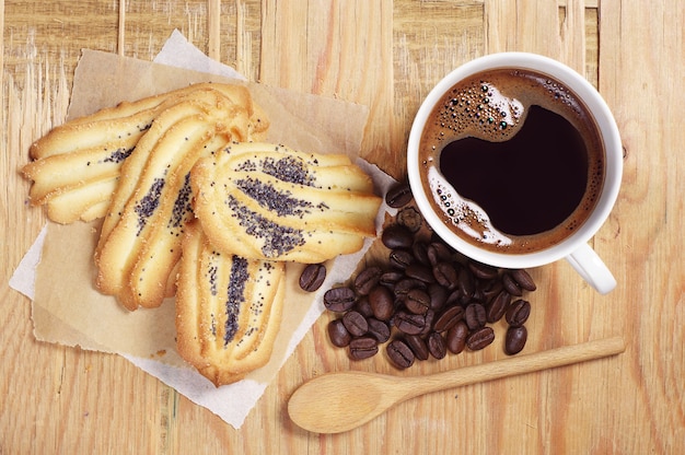 Чашка горячего кофе и печенье с маком на старых деревянных фоне, вид сверху