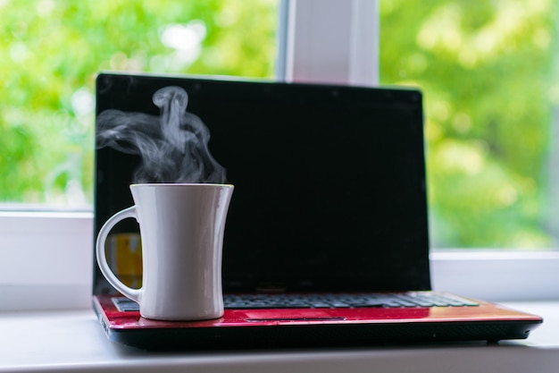 A cup of hot coffee on a laptop background