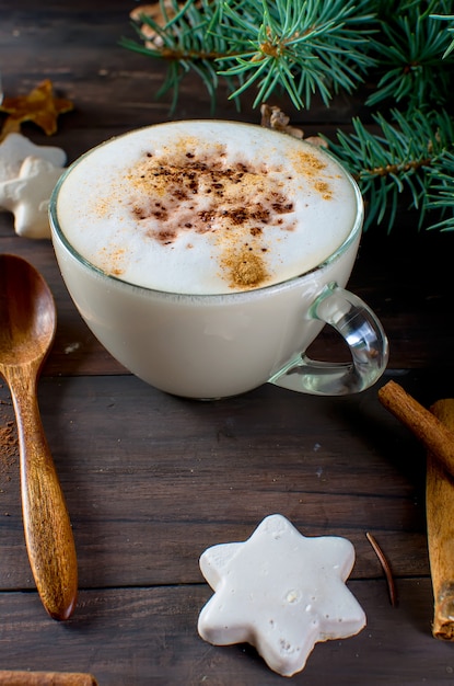 Cup of hot coffee latte, cinnamon, cookies and fir branches. 