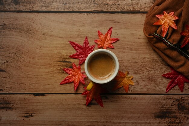 Cup of hot coffee and maple leaves on wooden table.Autumn season concept.