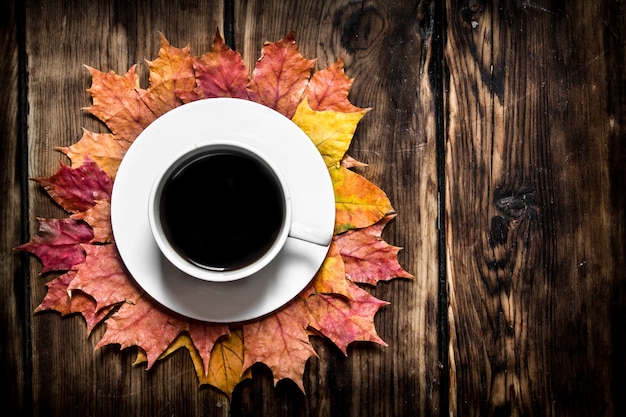 Cup of hot coffee with autumn leaves