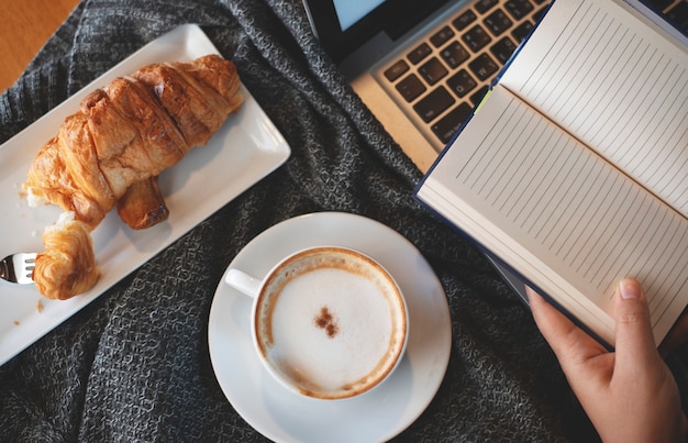 a cup of hot coffee with bakery on work table