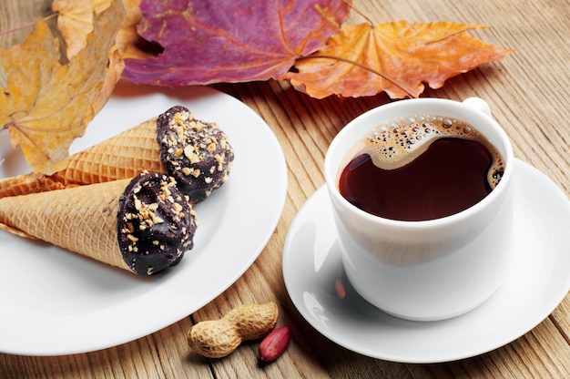 Cup of hot coffee with cakes in cones