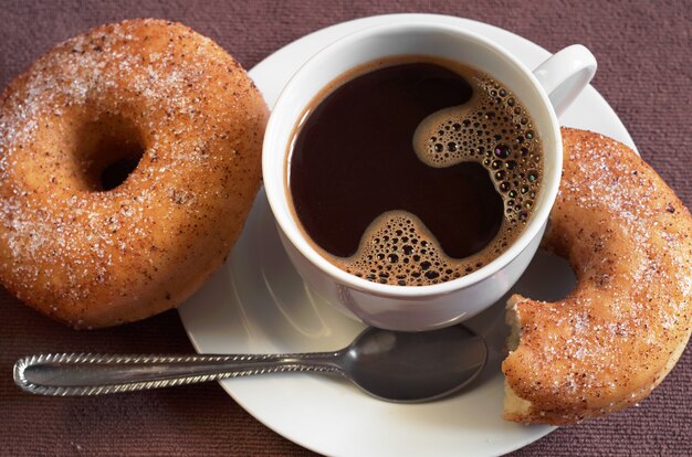 Photo cup of hot coffee with classic donuts on table close up. selective focus