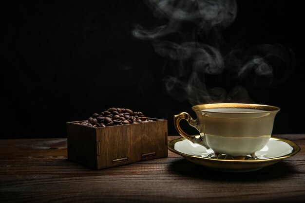 cup of hot coffee on a wooden surface on a black background