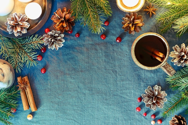 Cup of hot drink on christmas background. Cozy evening, mug of mulled wine, xmas decorations, candles and lights garlands.