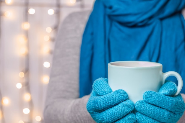 A cup of hot drink, in mittens. Christmas concept. Place for congratulations.