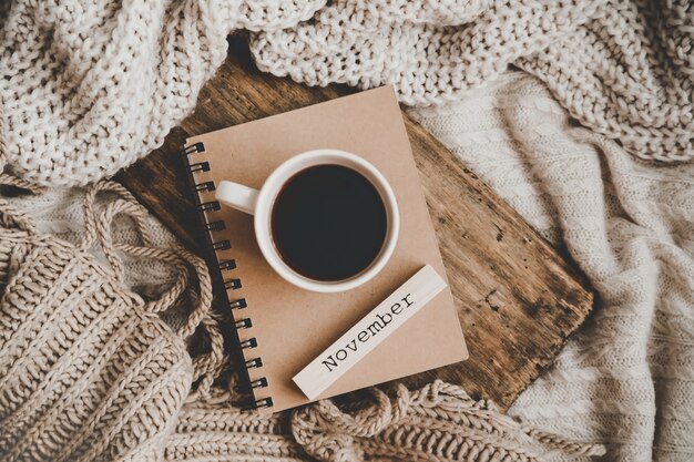 Cup of hot drink on notebookand knitting clothes