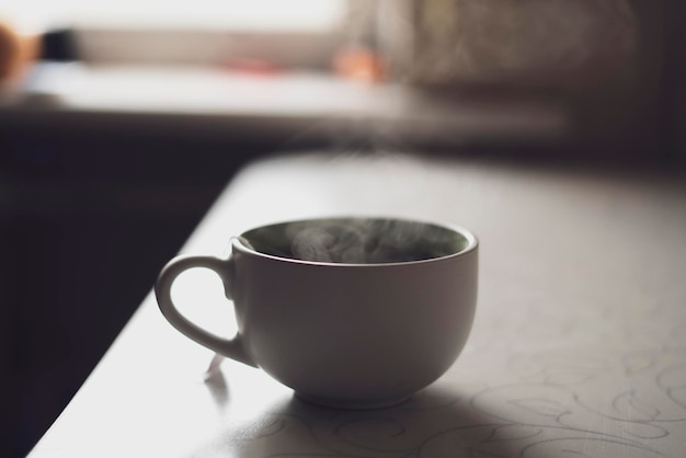 A cup of hot drink on the table with aromatic steam