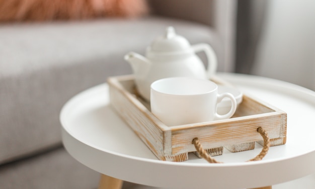 Photo cup of hot drink and teapot on a serving tray on table