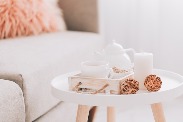 Cup of hot drink and teapot on a serving tray on table