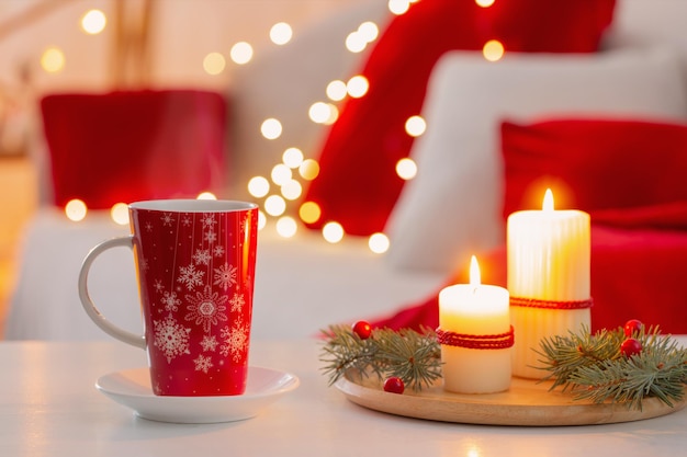 집에서 흰색과 붉은 색의 크리스마스 장식과 함께 뜨거운 음료 한잔
