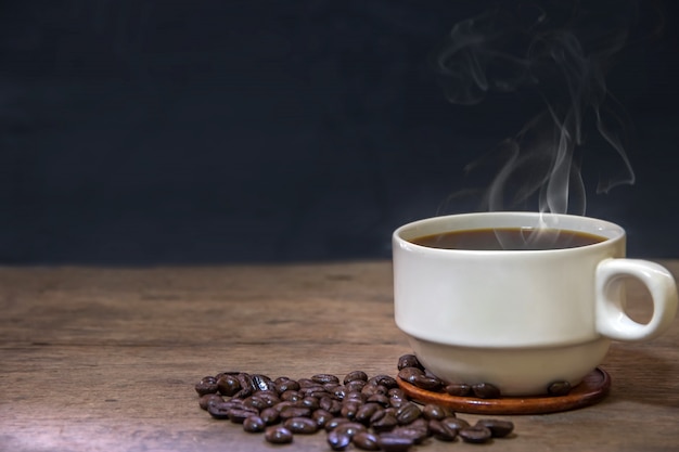 cup of hot espresso coffee mugs and roasted coffee beans placed on wooden floor