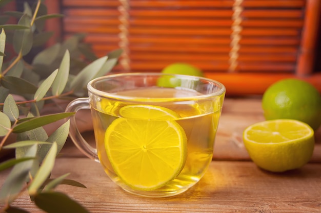 Cup of hot green tea with lime on the old wooden table