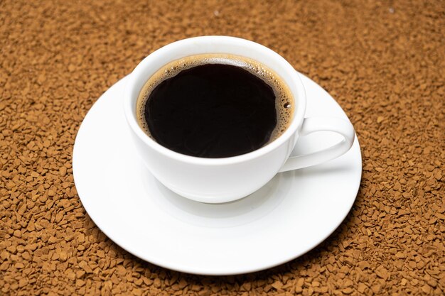 Чашка горячего растворимого кофе на фоне замороженных сухих гранул