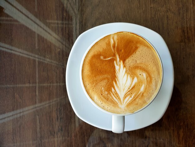 木製の背景にホットラテアートコーヒーのカップ