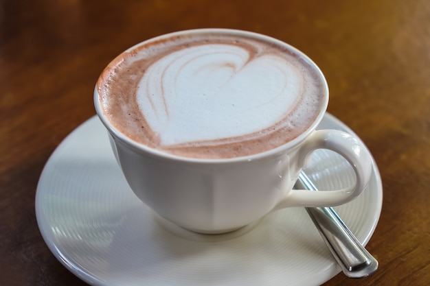 cup of hot latte art coffee on wooden table