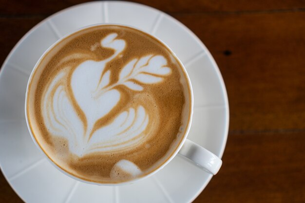 Photo a cup of hot latte art coffee on wooden table