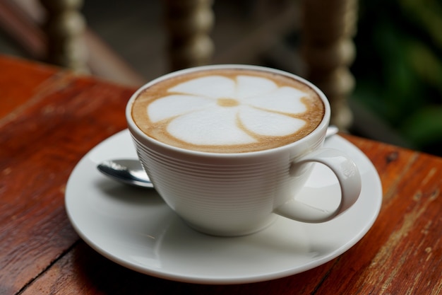 A cup of hot latte art coffee on a wooden table