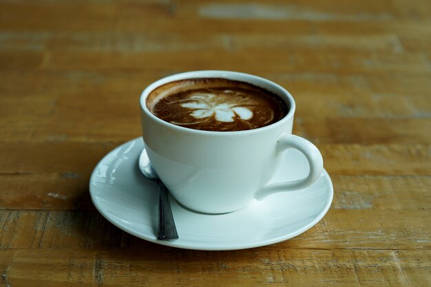 A cup of hot latte art coffee on wooden table